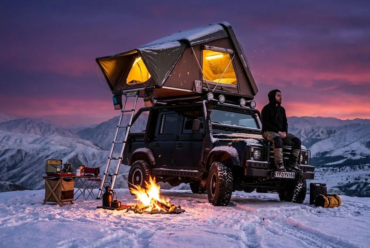 Tente de toit hiver montée sur un véhicule 4x4 en paysage alpin enneigé, feu de camp et matériel outdoor, ambiance nocturne.